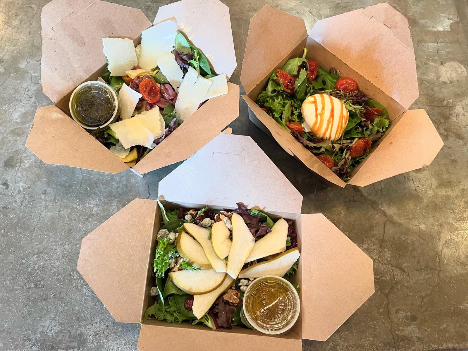 House, burrata and pear salads packed in takeout boxes